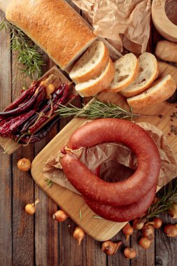 Biberiye, soğan ve biberli füme sosis. Ekmek ve baharatlı sosis eski ahşap bir masada. Üst görünüm.