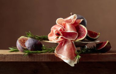 İncirli jambon ve ahşap bir masada biberiye. Boşluğu kopyala.