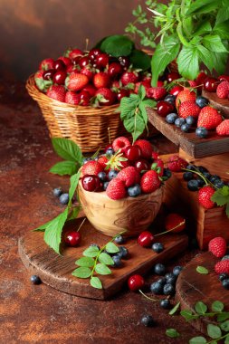 Yapraklı taze böğürtlen. Eski bir masada çilek, ahududu, yabanmersini ve tatlı kirazlar.. 