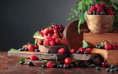 Yapraklı taze böğürtlen. Eski bir masada çilek, ahududu, yabanmersini ve tatlı kirazlar. Boşluğu kopyala.