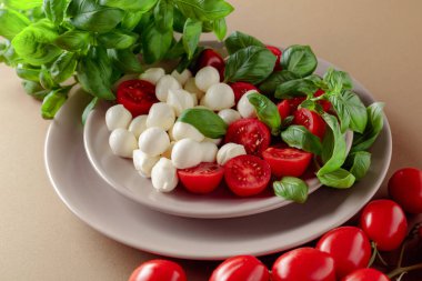 Domatesli Caprese salatası, kahverengi arka planda mini mozzarella ve fesleğen. İtalyan yemeği ve sağlıklı vejetaryen diyeti. 