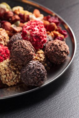 Ev yapımı çikolatalı, fındıklı, kurutulmuş meyveli, siyah bir masada..