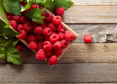 Eski ahşap arka planda yaprakları olan taze ahududular..