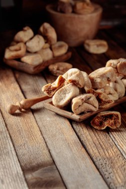 Eski ahşap bir masada, ahşap bir tabakta kurumuş incir. Boşluğu kopyala.