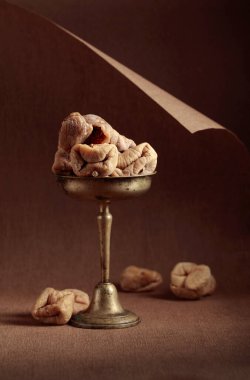 Kahverengi arka planda eski bir pirinç kapta kurutulmuş incir..