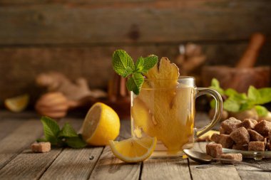 Malzemeli zencefil çayı. Zencefil, limon, nane ve esmer şeker eski ahşap bir masada.