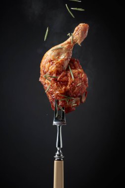 Siyah arka planda biberiye serpilmiş ızgara tavuk budu. Çataldaki tavuk budu..