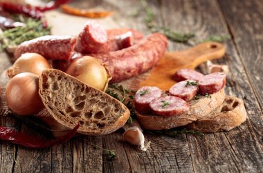 Eski ahşap bir masada sosisli sandviç. Kurutulmuş sosis, kekik, soğan, sarımsak ve biber.. 