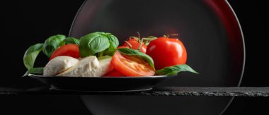 Siyah arka planda domates ve fesleğenli Mozzarella. Boşluğu kopyala.