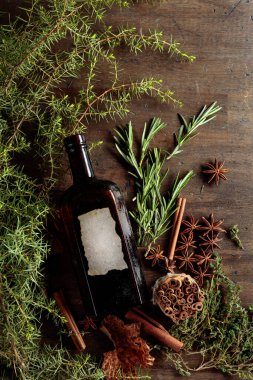 Eski bir ahşap masada antika bir şişe, otlar ve baharatlar. Eski boş bir şişede.