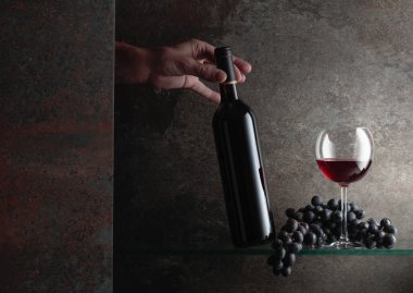 Bir şişe kırmızı şaraba uzanır. Pahalı şarapların konsepti. Metnin için boş yer.