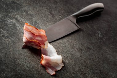 Mutfak bıçağında domuz pastırması. Greystone arkaplanı.
