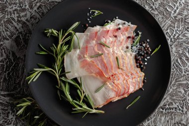 Siyah tabakta biberiye, tuz ve biberli domuz pastırması. Üst görünüm.