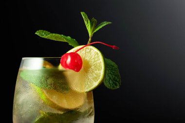 Limon dilimleri, nane ve kirazlı soğuk bir içecek. Dondurulmuş bardakta mojito ve konserve kirazla süslenmiş..