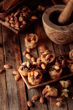 Eski ahşap bir masada bademli, kuru üzümlü ve ballı küçük kekler..