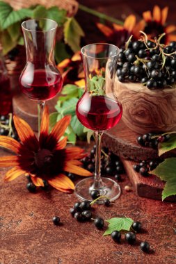 Siyah frenk üzümü likörü ve kahverengi bir masada olgun meyveler..