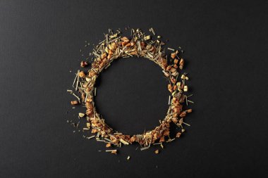 Bitki çayı siyah arka plana saçılmıştır. Yuvarlak kopya alanı. Üst görünüm.