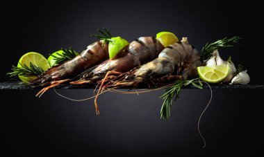 Limonlu taze kaplan karidesi, biberiye ve siyah arka planda sarımsak. Boşluğu kopyala.