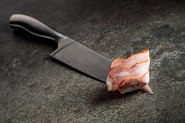 Mutfak bıçağında domuz pastırması. Greystone arkaplanı.
