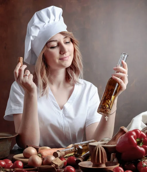 穿着厨师制服 拿着一小瓶橄榄油的年轻女人 各种香料和香草的橄榄油芬芳 — 图库照片