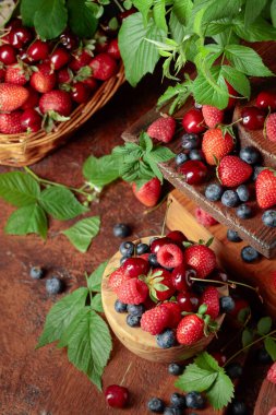 Yapraklı taze böğürtlen. Eski bir masada çilek, ahududu, yabanmersini ve tatlı kirazlar.. 