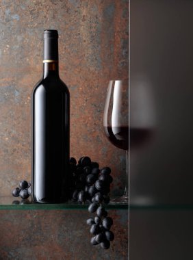 Bir şişe kırmızı şarap ve bir demet mavi üzüm..