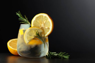 Limon dilimleri ve siyah arka planda biberiye dalıyla kokteyl cin toniği. Boşluğu kopyala.