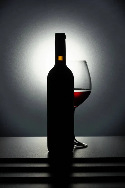 黒テーブルの上に赤ワインのボトルとガラス — ストック写真