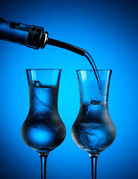Βότκα Χύνεται Από Μπουκάλι Ποτήρια Πάγο Κατεψυγμένα Γυαλιά Σκούρο Μπλε — Φωτογραφία Αρχείου