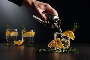 Limonlu ve biberiyeli kokteyl Cin ve Tonik. Barmen bardaktan bardağa kokteyl doldurur..