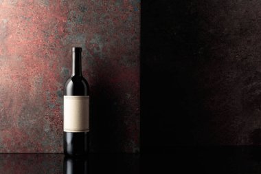 Paslı kahverengi arka planda eski boş etiketli bir şişe kırmızı şarap. Metnin için alanı olan ön görünüm.