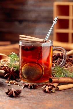 Tarçınlı, anasonlu ve kurutulmuş otlu Noel çayı. Kahverengi bir masada ardıç dallı bitki çayı..