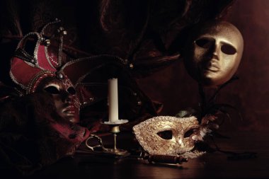 Karnaval maskeleri ve küçük pirinç şamdanlar eski ahşap bir masada..