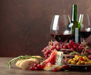 Prosciutto, mavi peynir ve koyu arkaplanda biberiyeli sandviç. Lezzetli aperatif ve kırmızı şarap. Metnin için boşluk kopyala.