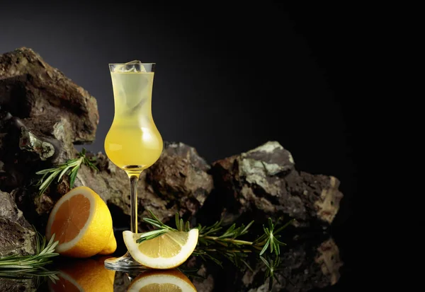 伝統的な自家製レモンリキュールのリモンチェッロと黒の反射的背景に新鮮な柑橘類 レモンスライスとローズマリーの枝を持つイタリアの伝統的なリキュールのリモンチェッロ — ストック写真