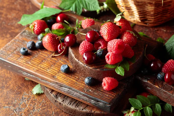 Yapraklı taze böğürtlen. Eski bir masada çilek, ahududu, yabanmersini ve tatlı kirazlar.. 