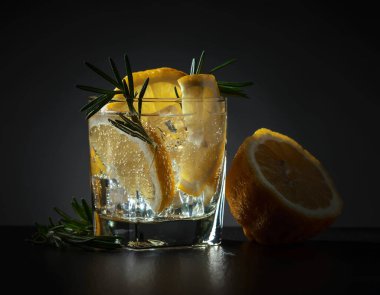 cin-tonik, limon ve biberiye koyu arka plan üzerinde.