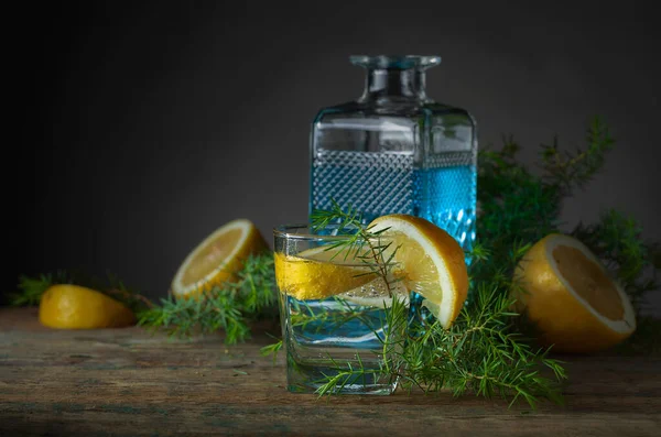 古い木製のテーブルの上に青いジン 強壮剤 レモンとカクテル レモンスライスとジュニパーブランチとアルコール飲料 — ストック写真