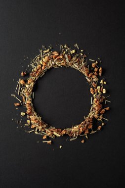 Bitki çayı siyah arka plana saçılmıştır. Yuvarlak kopya alanı. Üst görünüm.