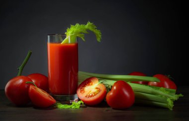 Domatesli domates suyu ve koyu arkaplanda kereviz çubukları..