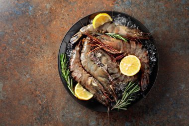 Limonlu, biberiyeli ve ezilmiş buzlu taze kaplan karidesleri. Paslı metal arkaplan.