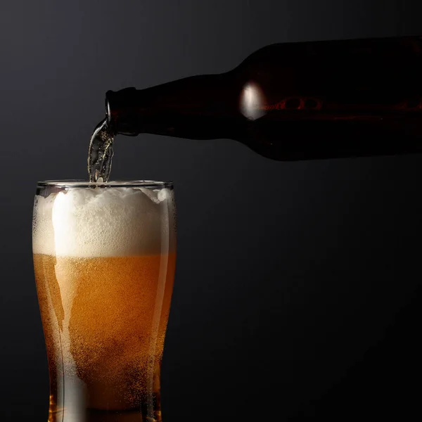 Birra Viene Versata Una Bottiglia Bicchiere Uno Sfondo Nero — Foto Stock