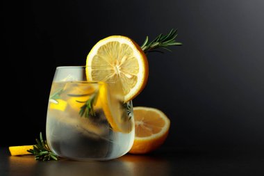 Limon dilimleri ve siyah arka planda biberiye dalıyla kokteyl cin toniği. Boşluğu kopyala.