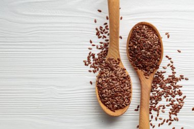 Beyaz ahşap arka planda keten tohumu olan tahta kaşıklar. Üst Manzara. Boşluğu kopyala.