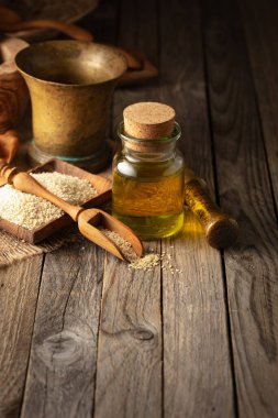 Susam tohumu ve yağ. Eski ahşap bir masada mutfak aletleriyle susam yağı..