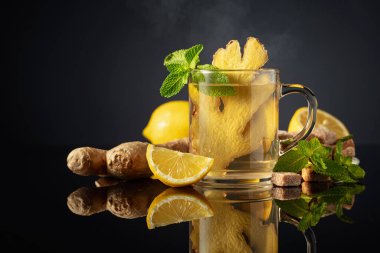 Malzemeli zencefil çayı. Siyah arka planda zencefil, limon, nane ve esmer şeker. Boşluğu kopyala.