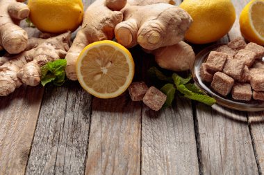 Zencefilli çay için malzemeler. Zencefil, limon, nane ve esmer şeker eski ahşap bir masada..