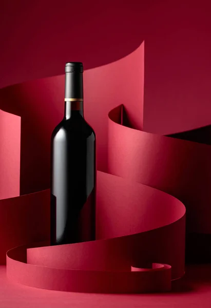 赤い背景に赤ワインの未開封のボトル — ストック写真