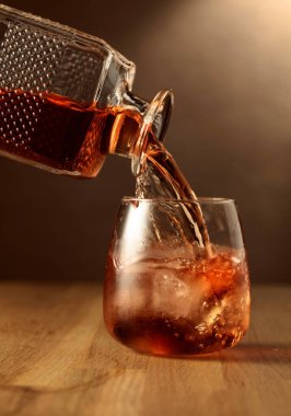 Viski bardağa doğal buzla doldurulur. Meşe ağacının üstünde bir bardak viski..