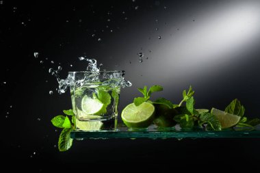 Limonlu mojito ve naneli kokteyl. Bir dilim kireç cama düşer ve güzel bir su sıçratır..